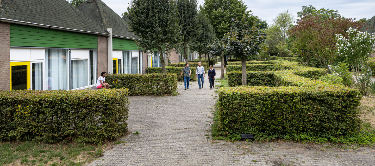 3 mensen lopen over terrein azc