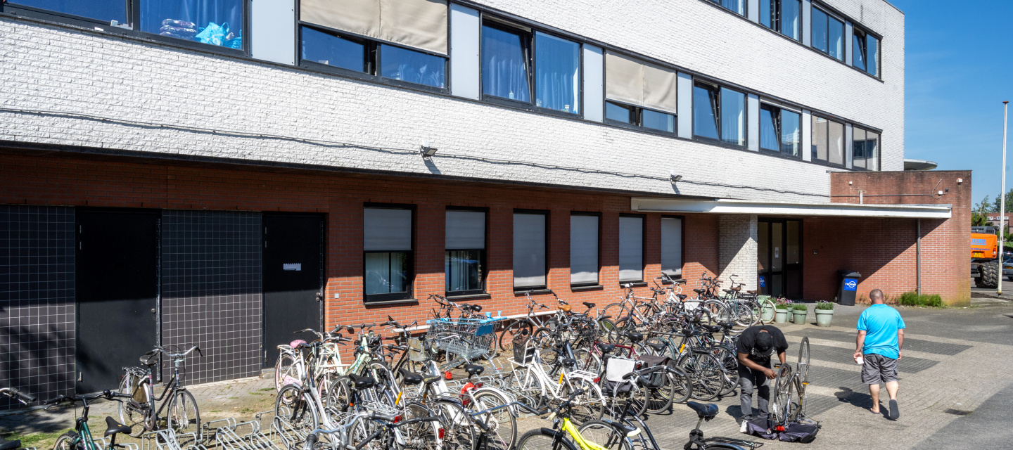 opvanglocatie in een gebouw met 2 verdiepingen, met veel fietsen voor de ingang geparkeerd