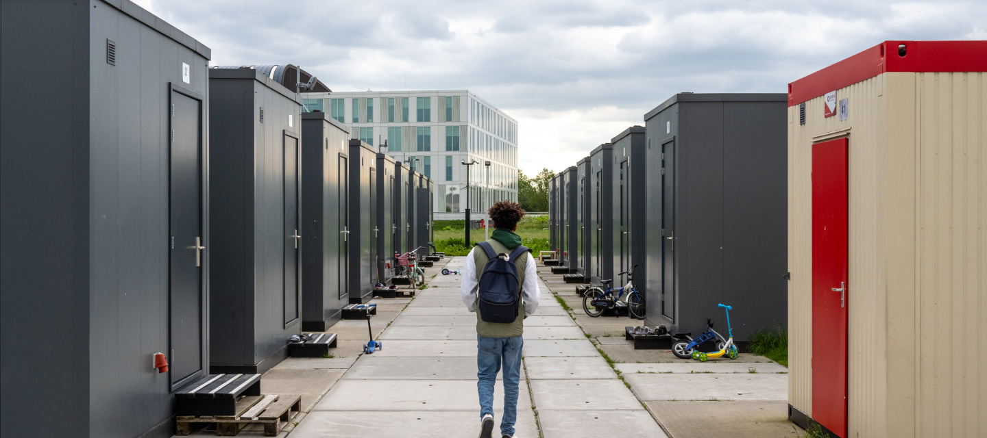Een minderjarige jongen loopt door de straat met containerwoningen in de noodopvang. 