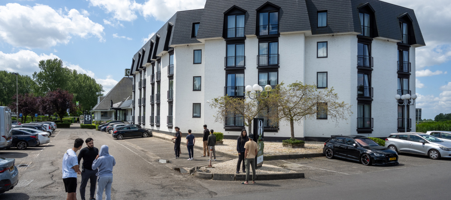 Minderjarige asielziekers staan buiten voor het hotel waar zij opgevangen worden