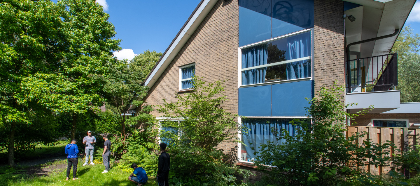 Woonhuis met in de tuin vier minderjarige jongens met een medewerker