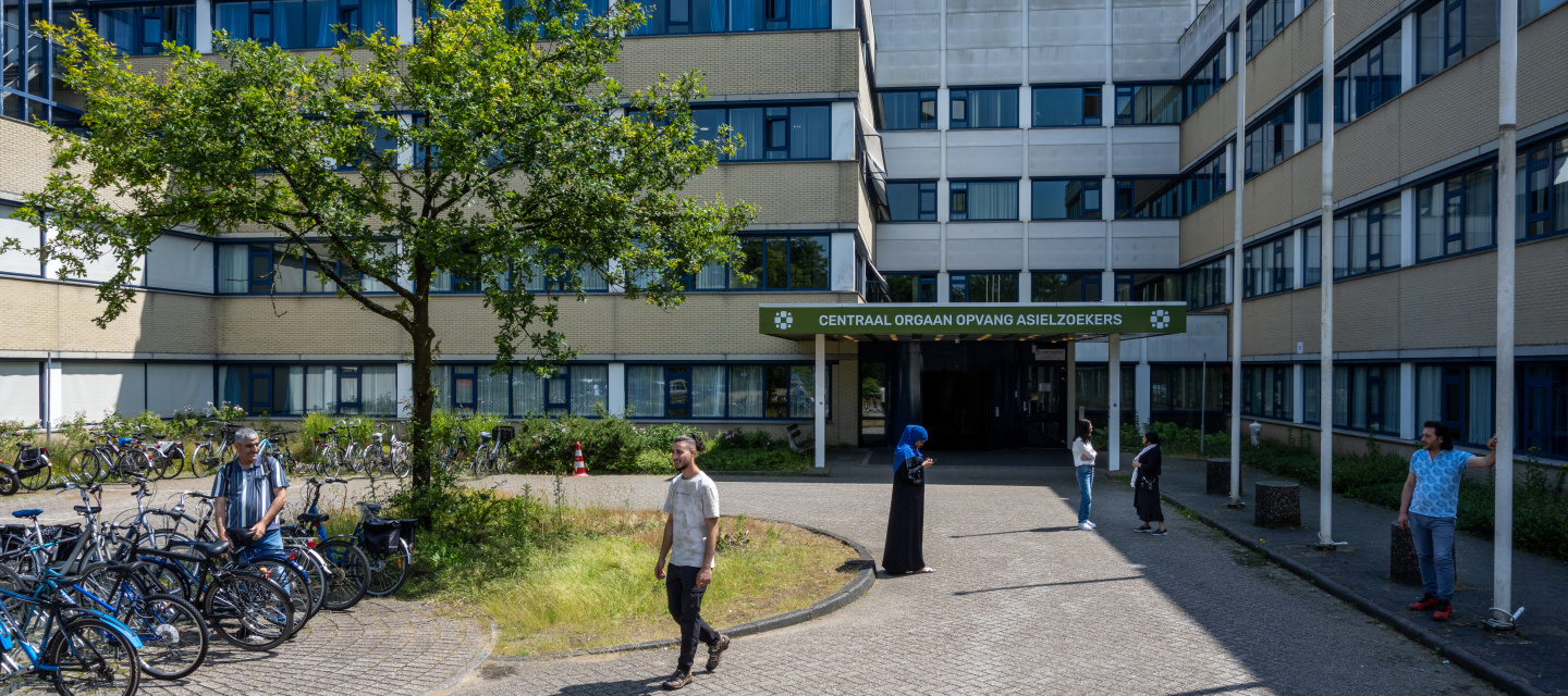 Coa noodopvang in een oud ziekenhuisgebouw, er staan mensen en fietsen voor de ingang
