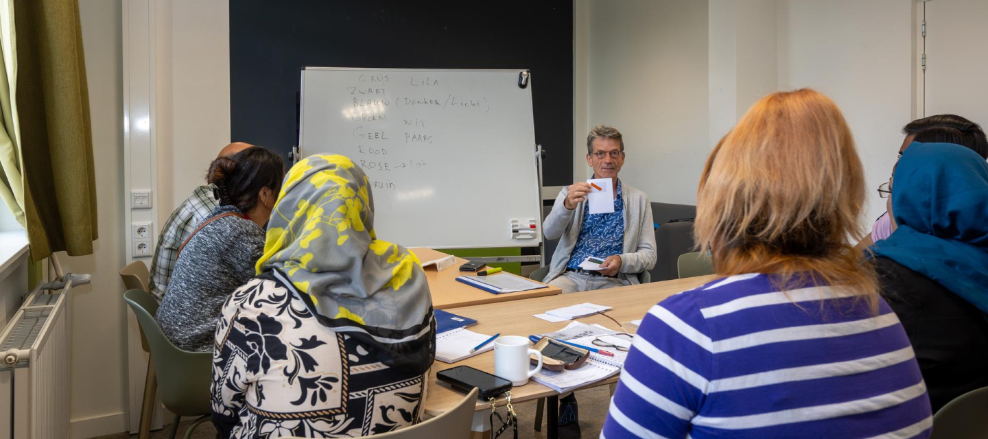 docent geeft taalles aan bewoners