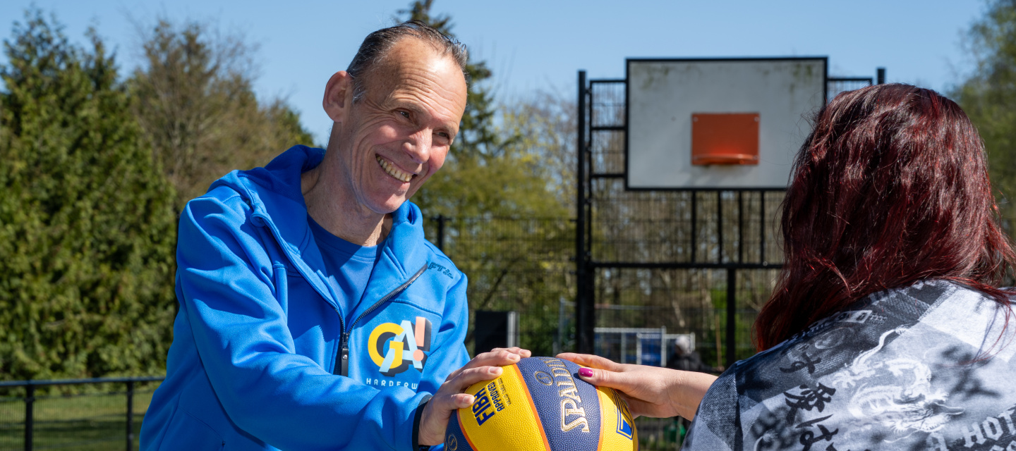 trainer geeft bal aan bewoner