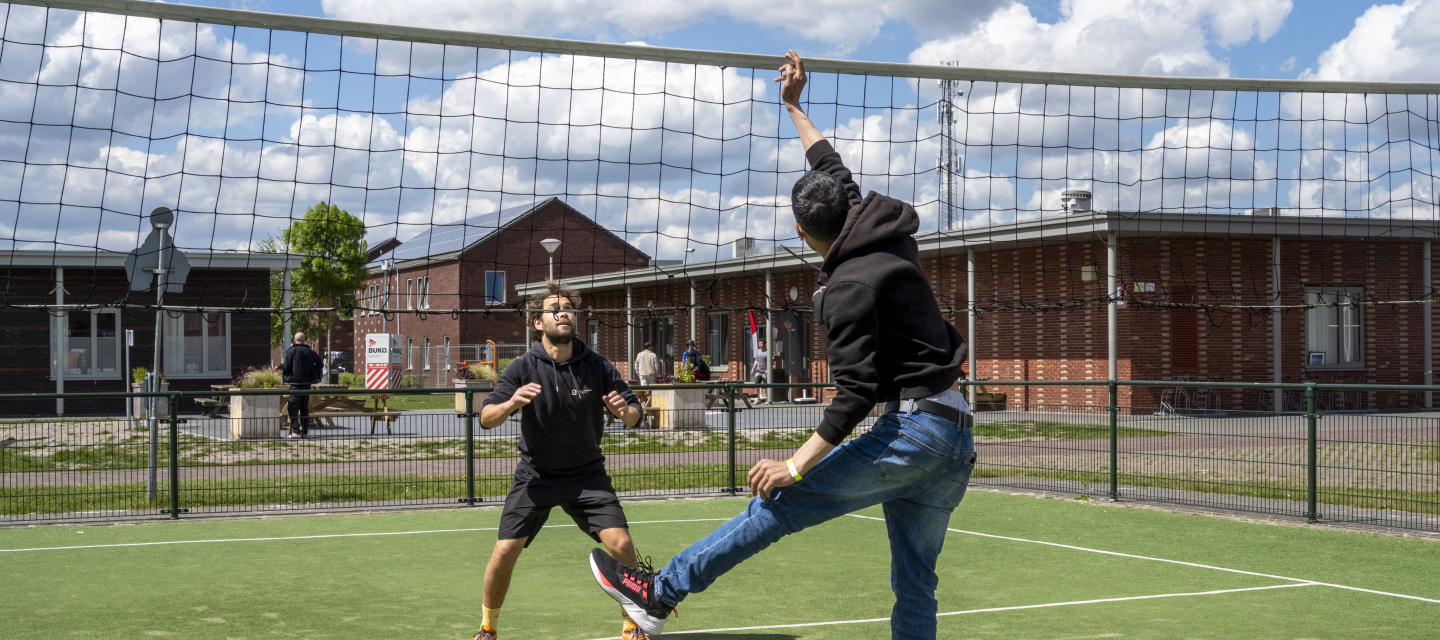 sporters buiten in actie bij volleybal net