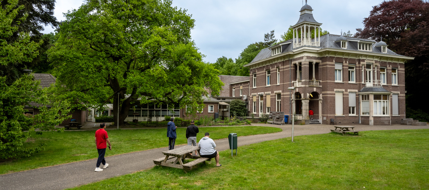 gebouw coa locatie wageningen keijenbergseweg, op de voorgrond bewoners op het grasveld en de picknicktafel