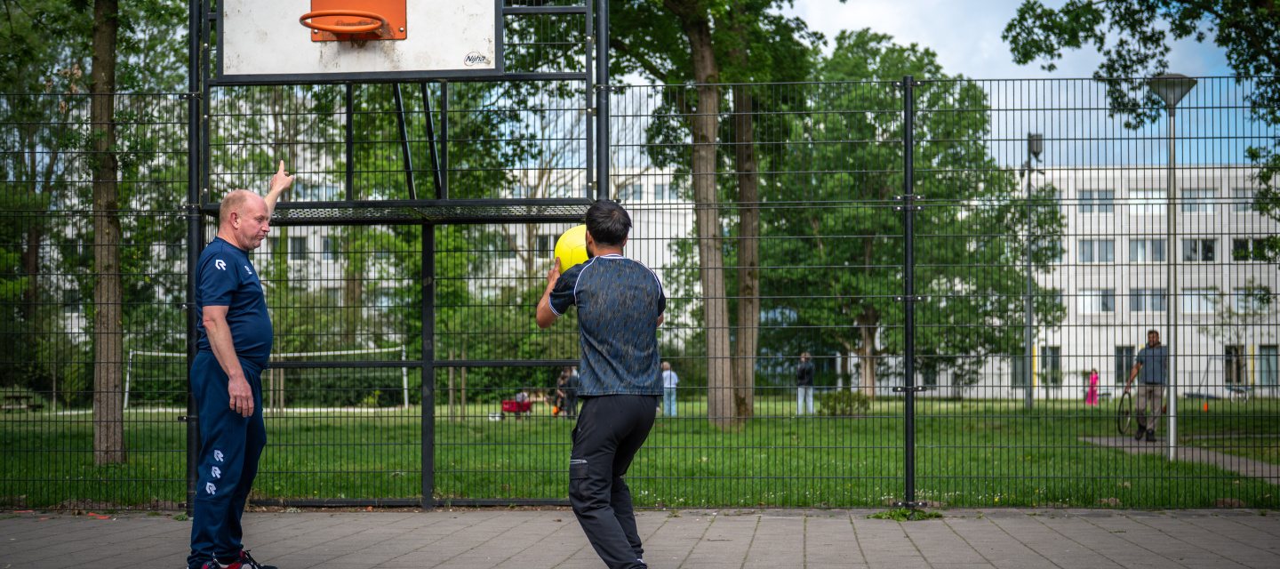 coach en bewoner basketballen voor het azc