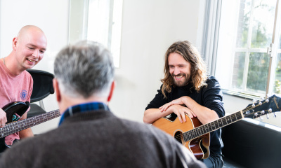 drie mannen spelen muziek in azc