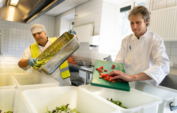 Daan Zagers met een bewoner aan het werk in de keuken van azc Gilze