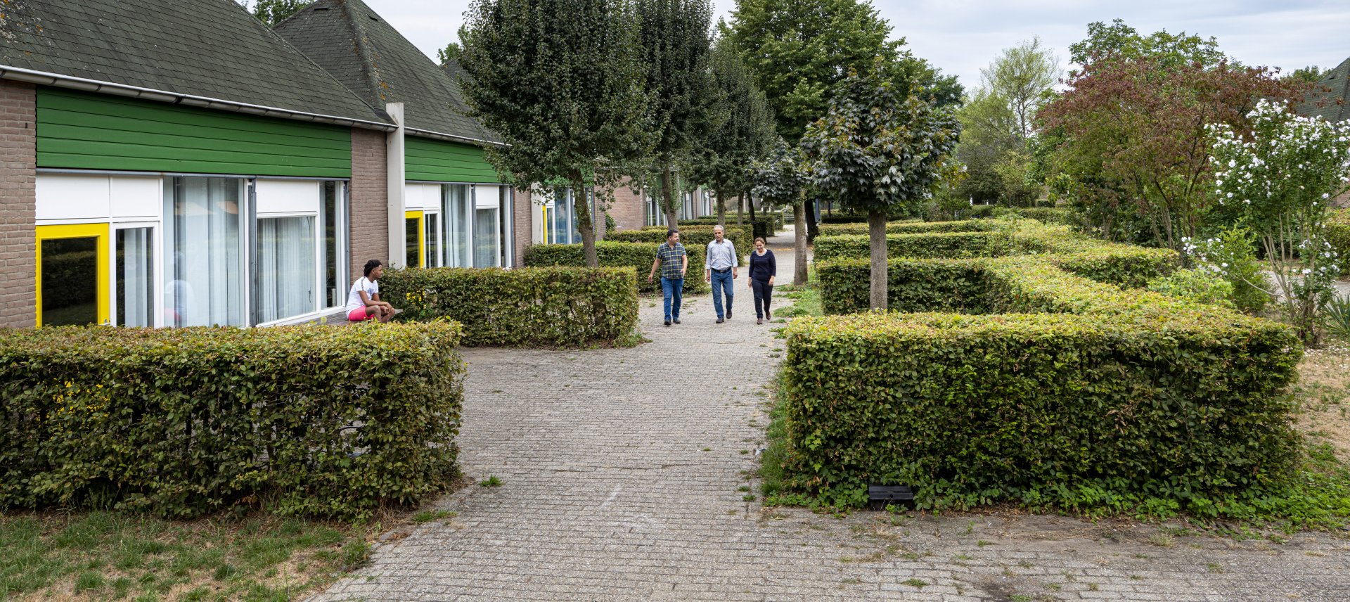 3 mensen lopen over terrein azc