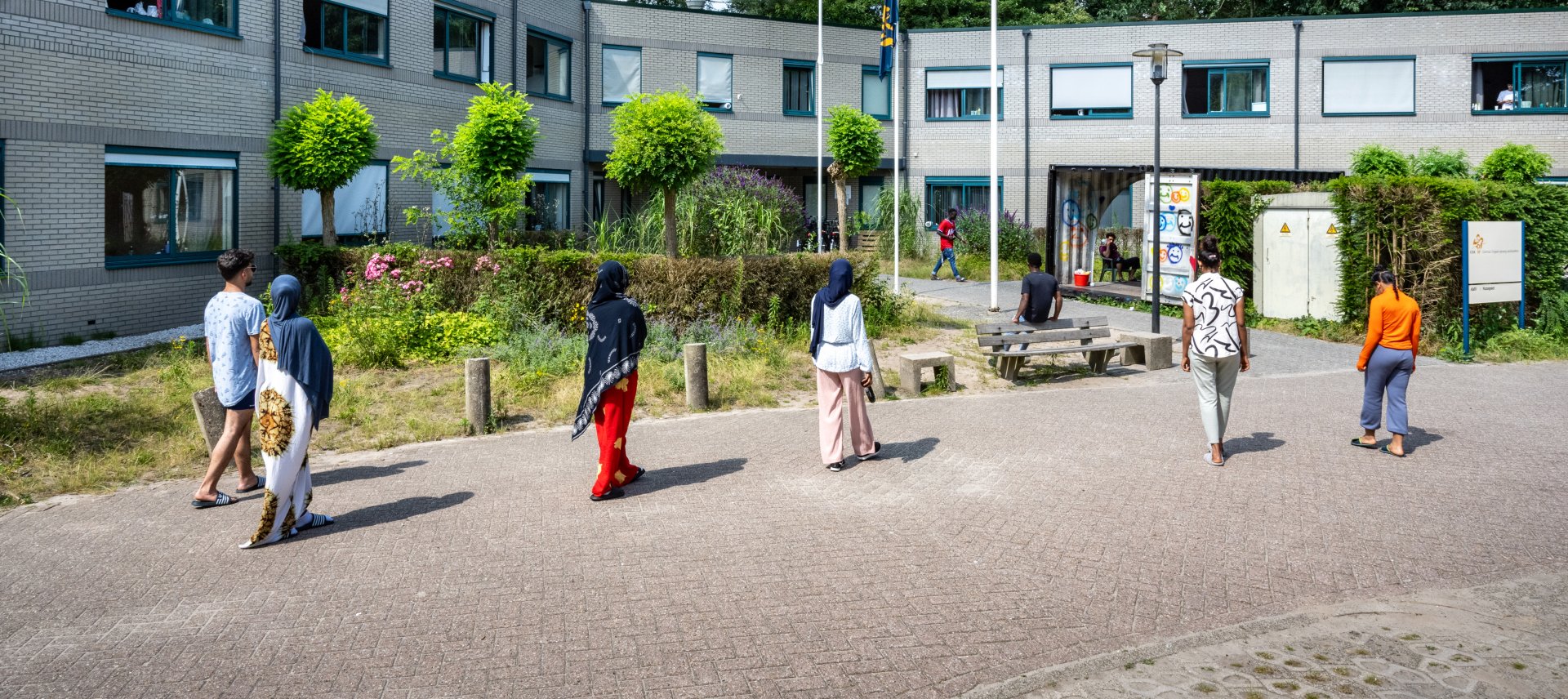 6 asielzoekers waarvan 1 man en 5 vrouwen lopen richting de ingang van het asielzoekerscentrum in Nunspeet