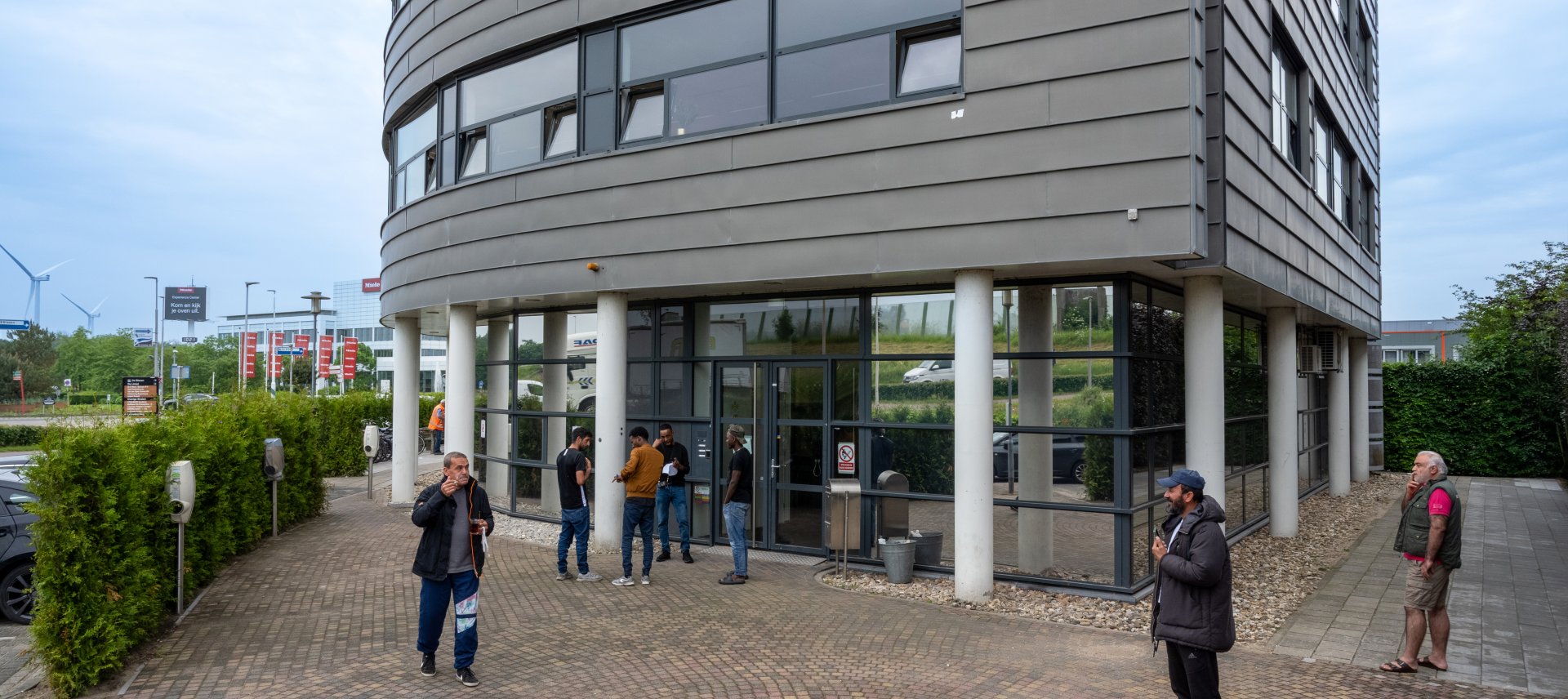 Asielzoekers en statushouders staan voor de ingang van de flat waarin de noodopvang is.