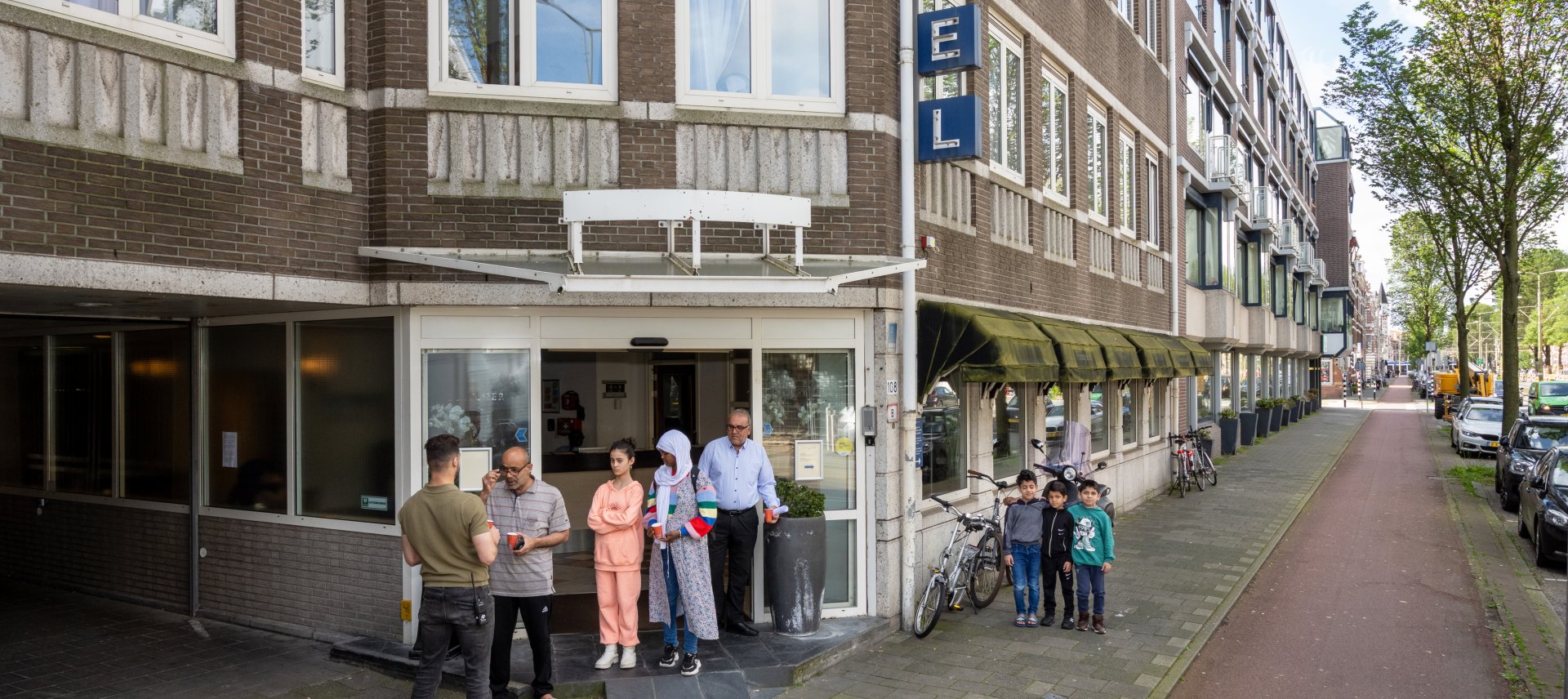 Statushouders staan voor de ingang van het hotel waar zij opgevangen worden in een straat in Den Haag.
