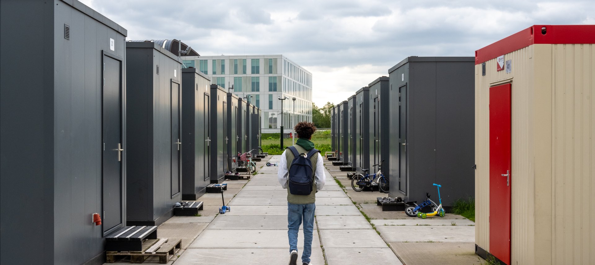Een minderjarige jongen loopt door de straat met containerwoningen in de noodopvang. 