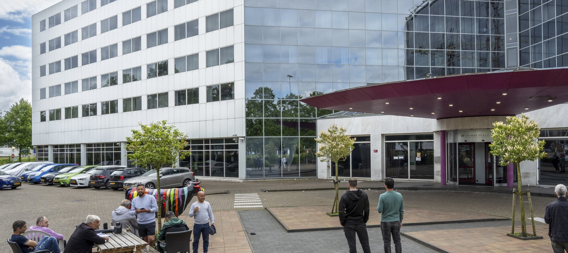 Asielzoekers en medewerkers zitten voor de ingang van de noodopvang.