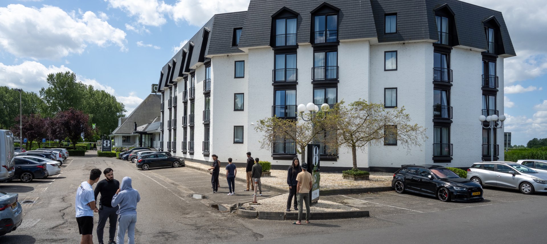Minderjarige asielziekers staan buiten voor het hotel waar zij opgevangen worden