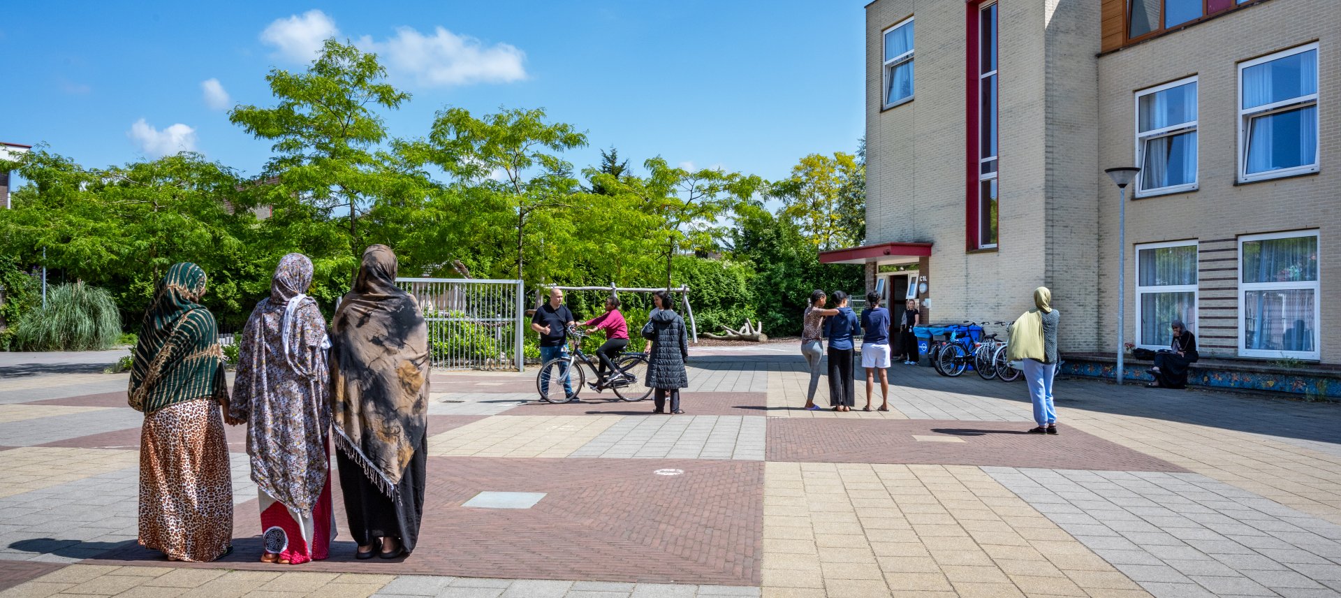 Minderjarige meisjes op het plein voor de locatie waar 1 van hen fietsles krijgt.