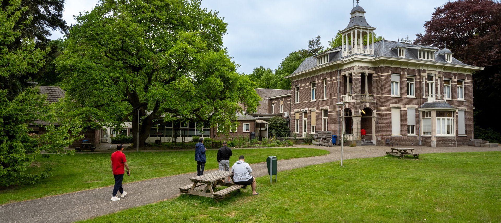 gebouw coa locatie wageningen keijenbergseweg, op de voorgrond bewoners op het grasveld en de picknicktafel