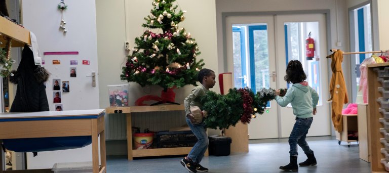 Asielzoekerskinderen sjouwen met een kerstboom op school