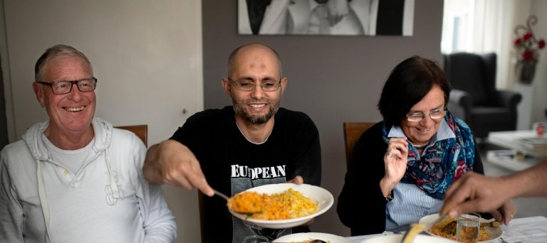 Asielzoeker eet een maaltijd met zijn buddy's