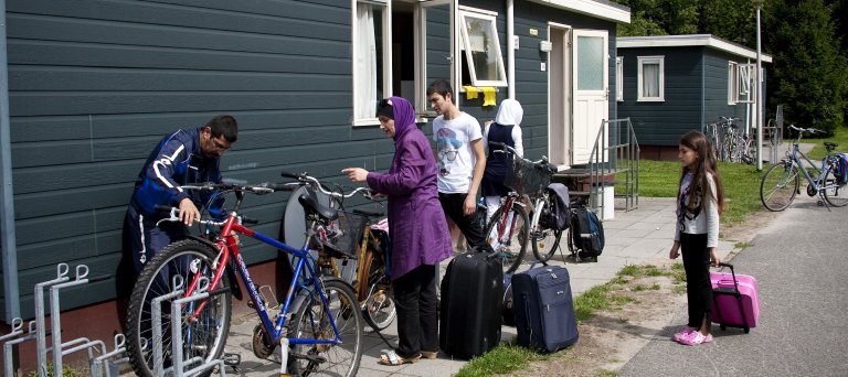 Gezin staat met koffers voor hun woning in het azc 
