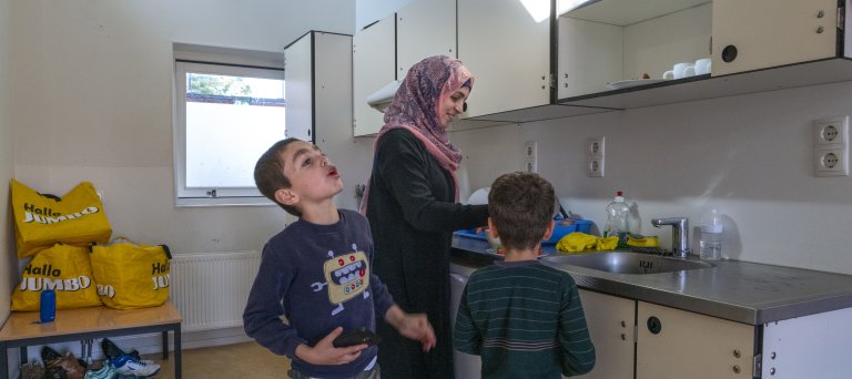 Moeder en kinderen in hun keuken in het azc