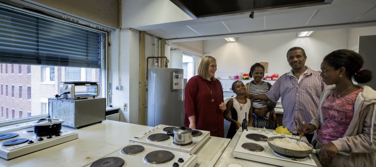 COA-medewerker in gesprek met een gezin in de keuken