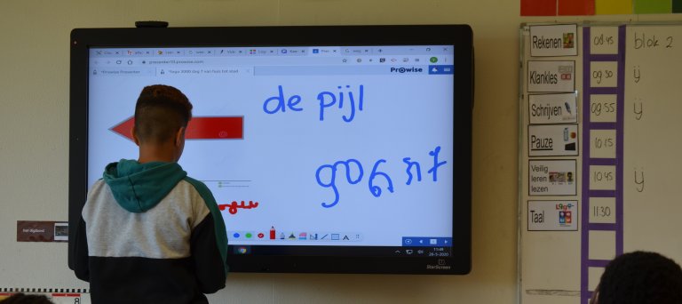 jongetej voor schoolbord met tekst in Nederlands en Tigrinya