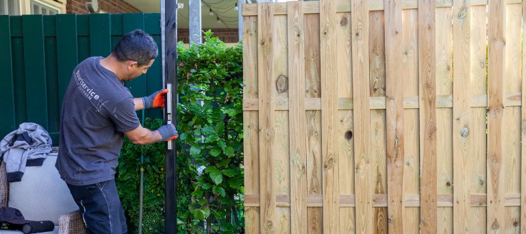 Man klust in iemands tuin, staat voor schutting