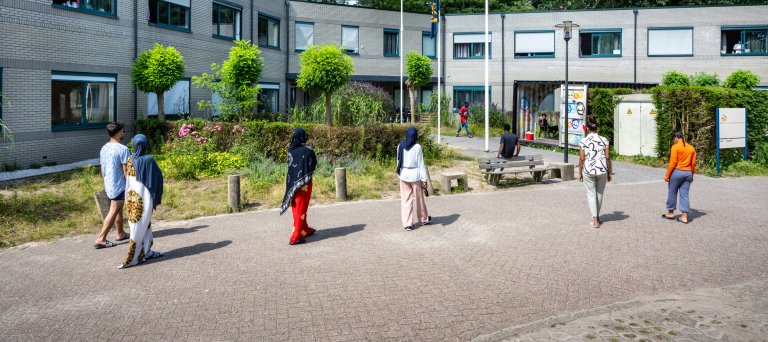 6 asielzoekers waarvan 1 man en 5 vrouwen lopen richting de ingang van het asielzoekerscentrum in Nunspeet