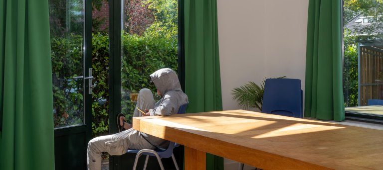 Jongen met capuchon op kijkt naar buiten