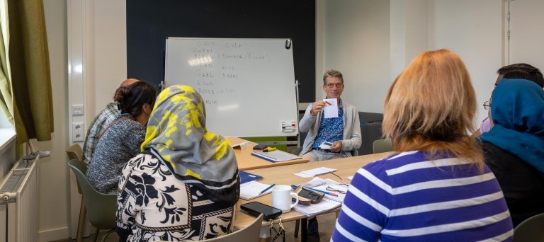 docent geeft taalles aan bewoners