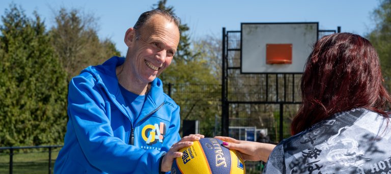 trainer geeft bal aan bewoner