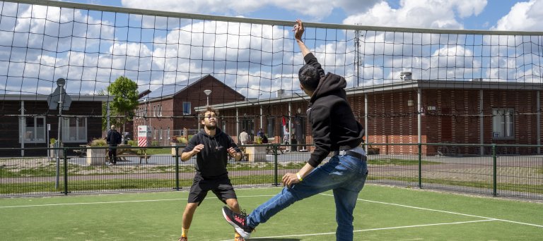 sporters buiten in actie bij volleybal net