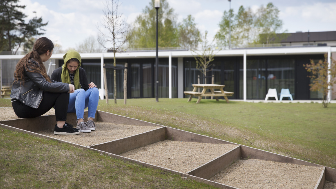 twee jongeren zitten in tuin van gesloten gezinsvoorziening