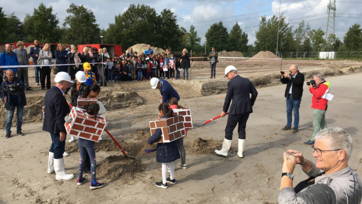 Kinderen verkleed als bakstenen graven het eerste gat