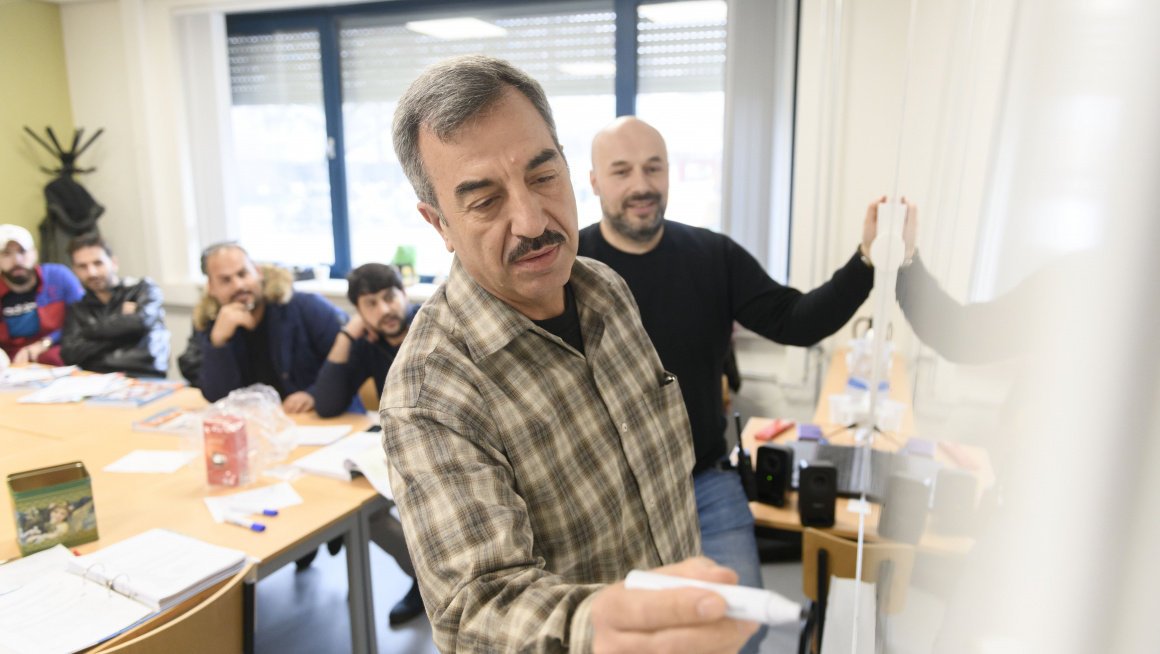 Statushouder schrijft op whiteboard tijdens les Kennis van de Nederlandse Maatschappij