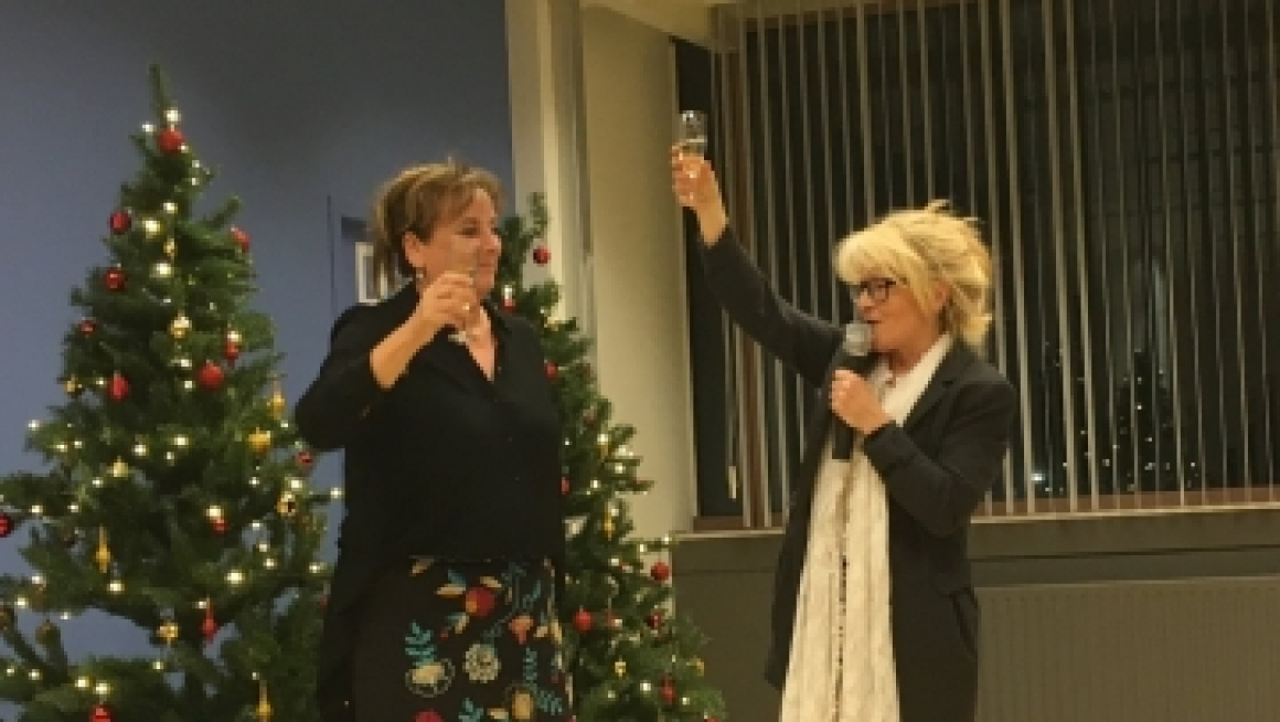 2 dames staan bij de kerstboom met een glas