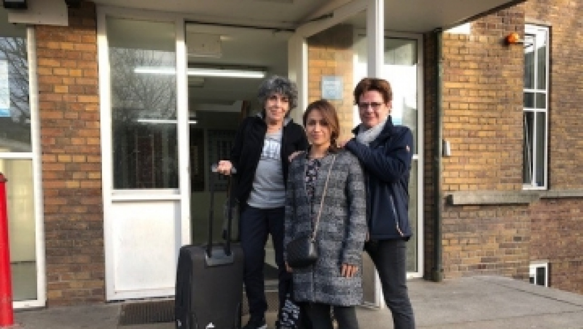 3 dames poseren voor een deur met een koffer