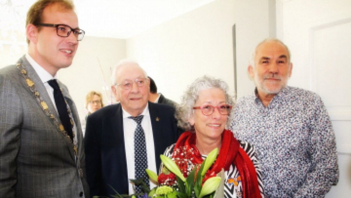 Vrouw poseert met de burgemeester en een bos bloemen