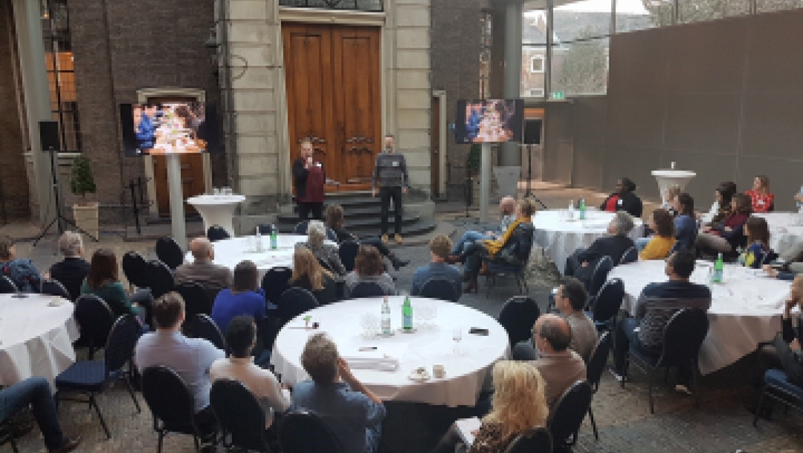 Mensen zitten aan een tafel in een zaal