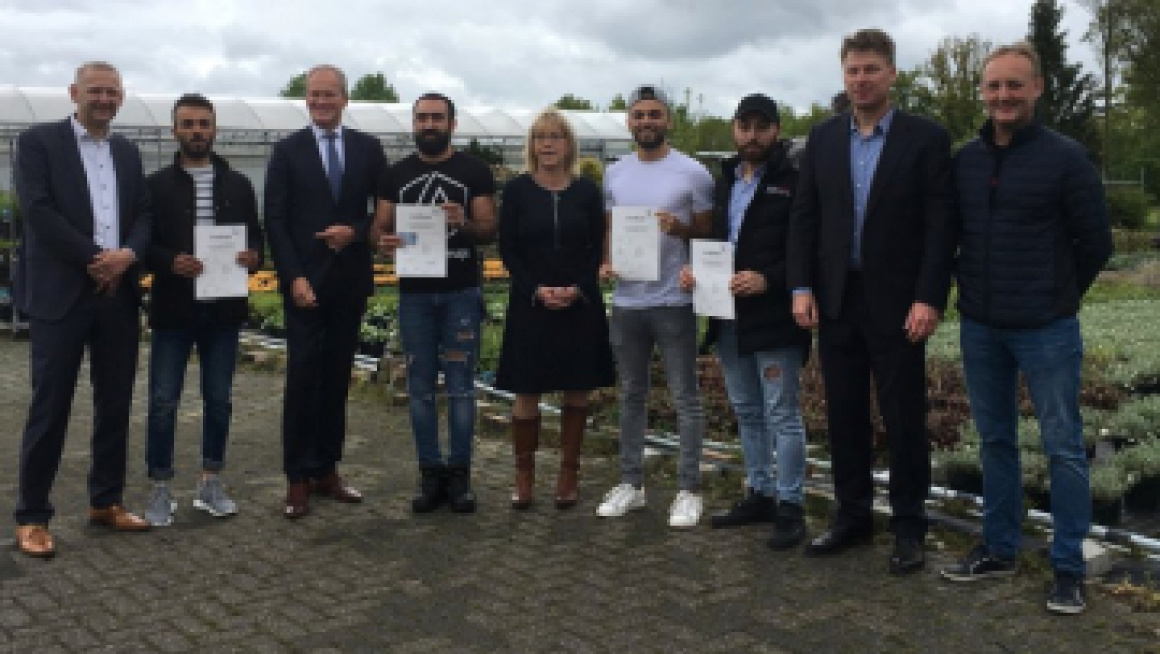 Gerard Bakker poseert met bewoners die diploma gehaald hebben