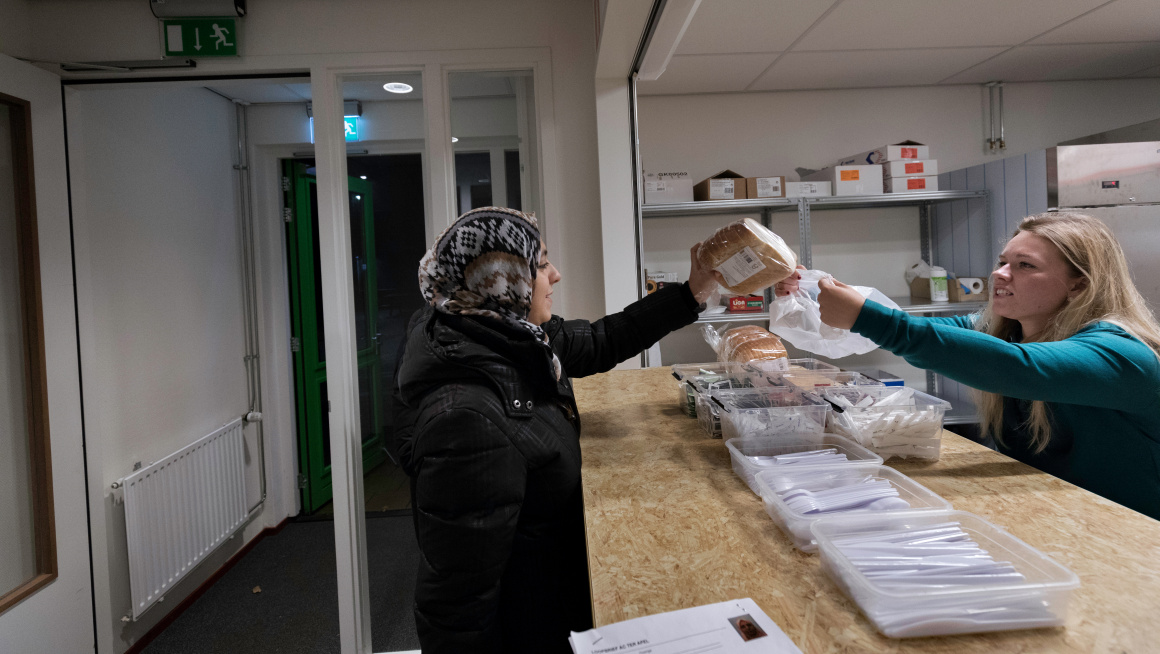 Vrouw ontvangt broodmaaltijd in de centrale ontvangstlocatie