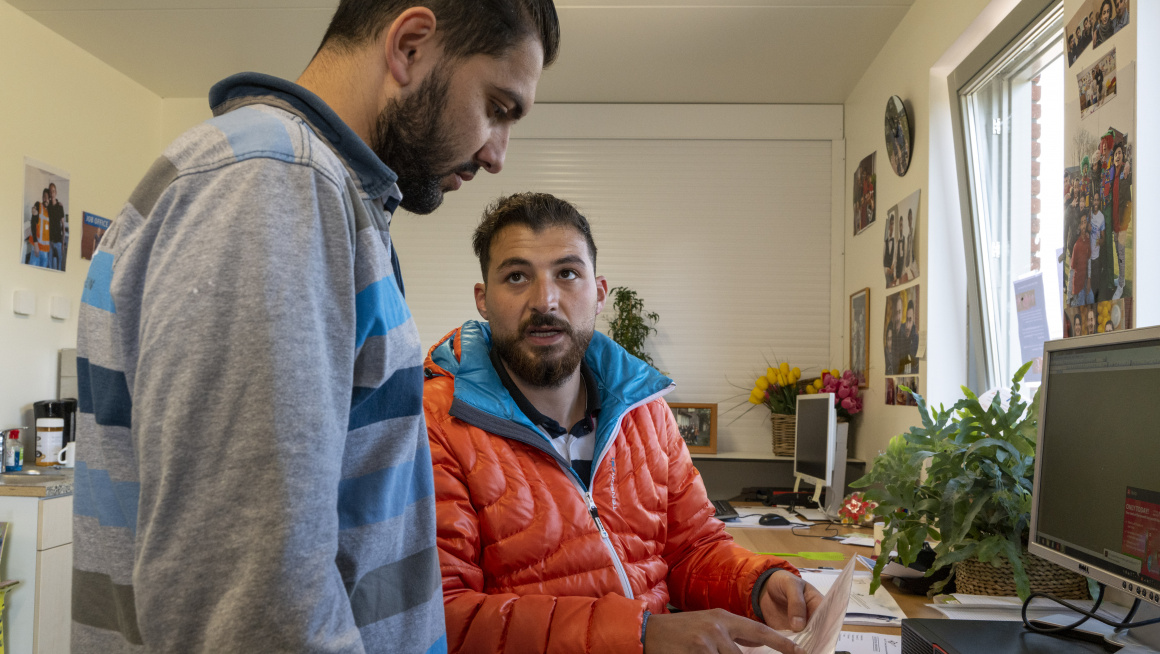 man laat andere man een papier zien