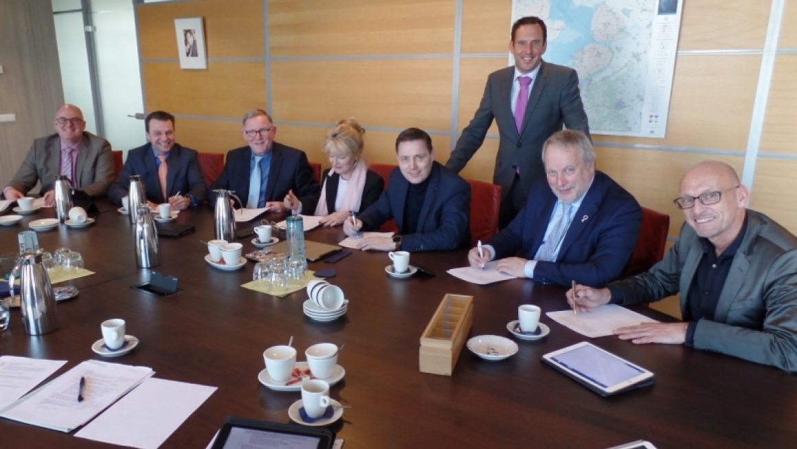 groep mensen poseert aan een vergadertafel