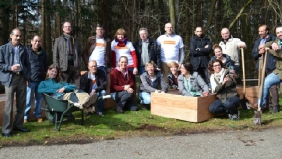 groep mensen poseert met schoffels en sommige zitten in een kar of bak