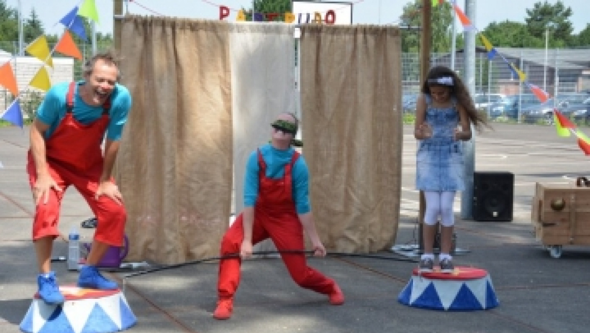 een circusartiest doet truukjes met twee kinderen