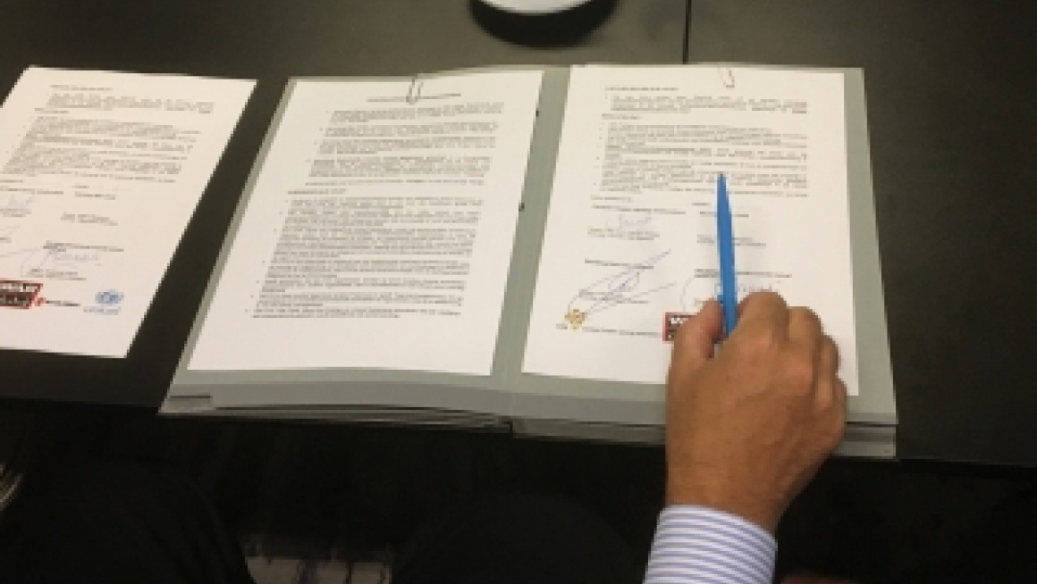 Contract wordt getoond met een hand met pen erboven