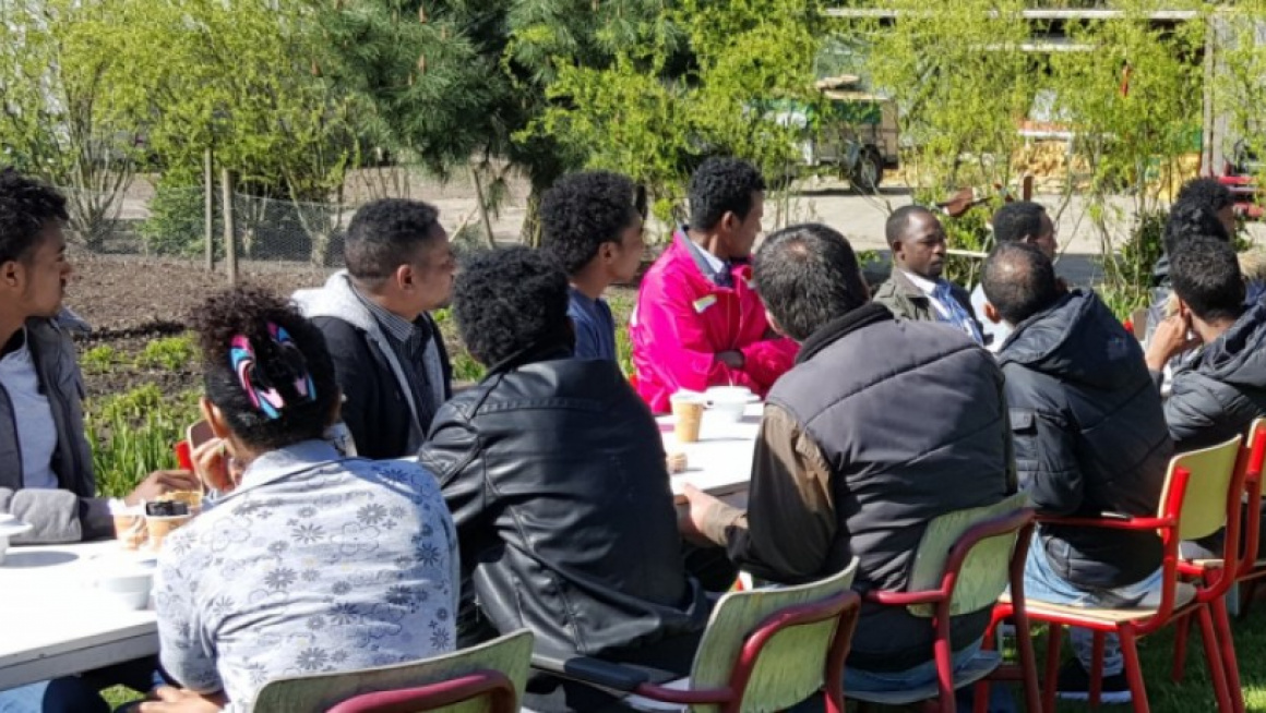 groep mensen zitten aan tafel en luisteren naar een man