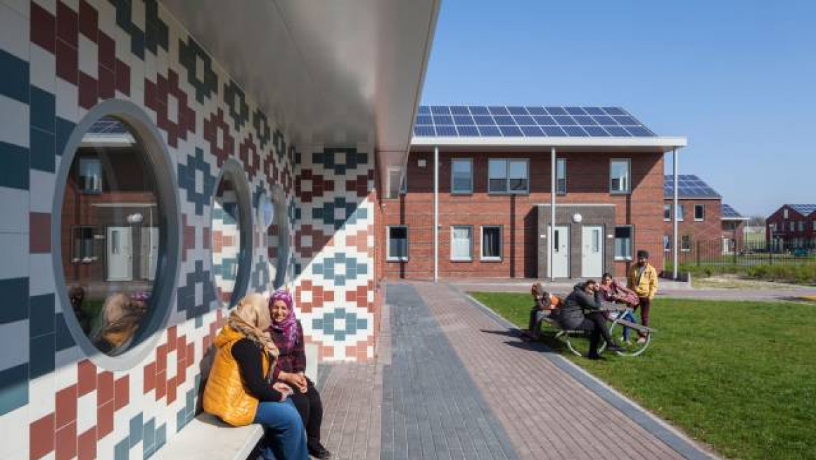 bewoners van azc voor het pand met zonnepanelen